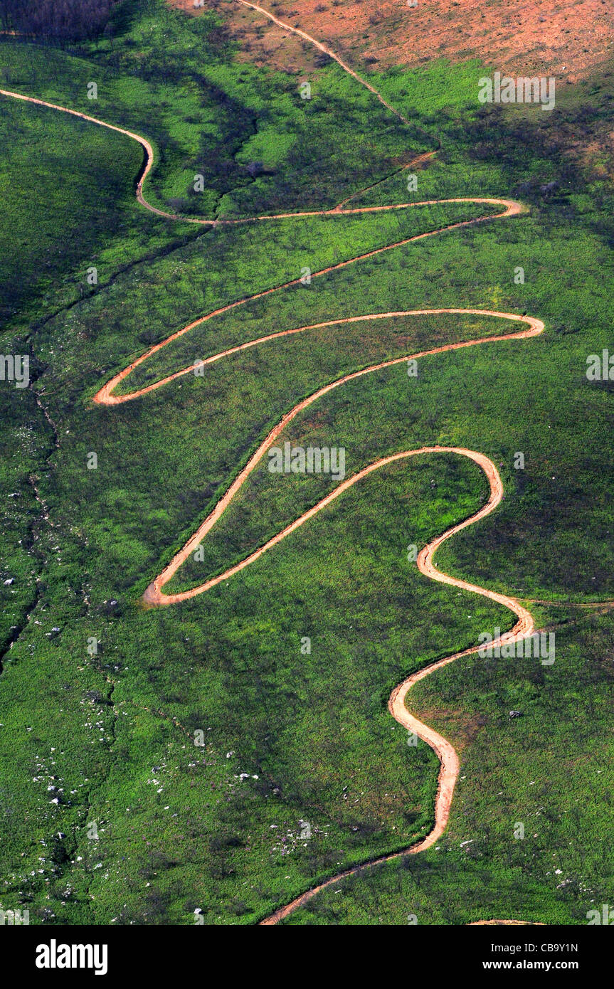 Winding mountain road makes its snake like path from the valley below up to higher ground Stock Photo