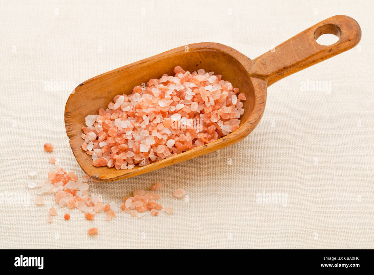 coarse crystals of pink and orange Himalayan salt on rustic wooden scoop Stock Photo