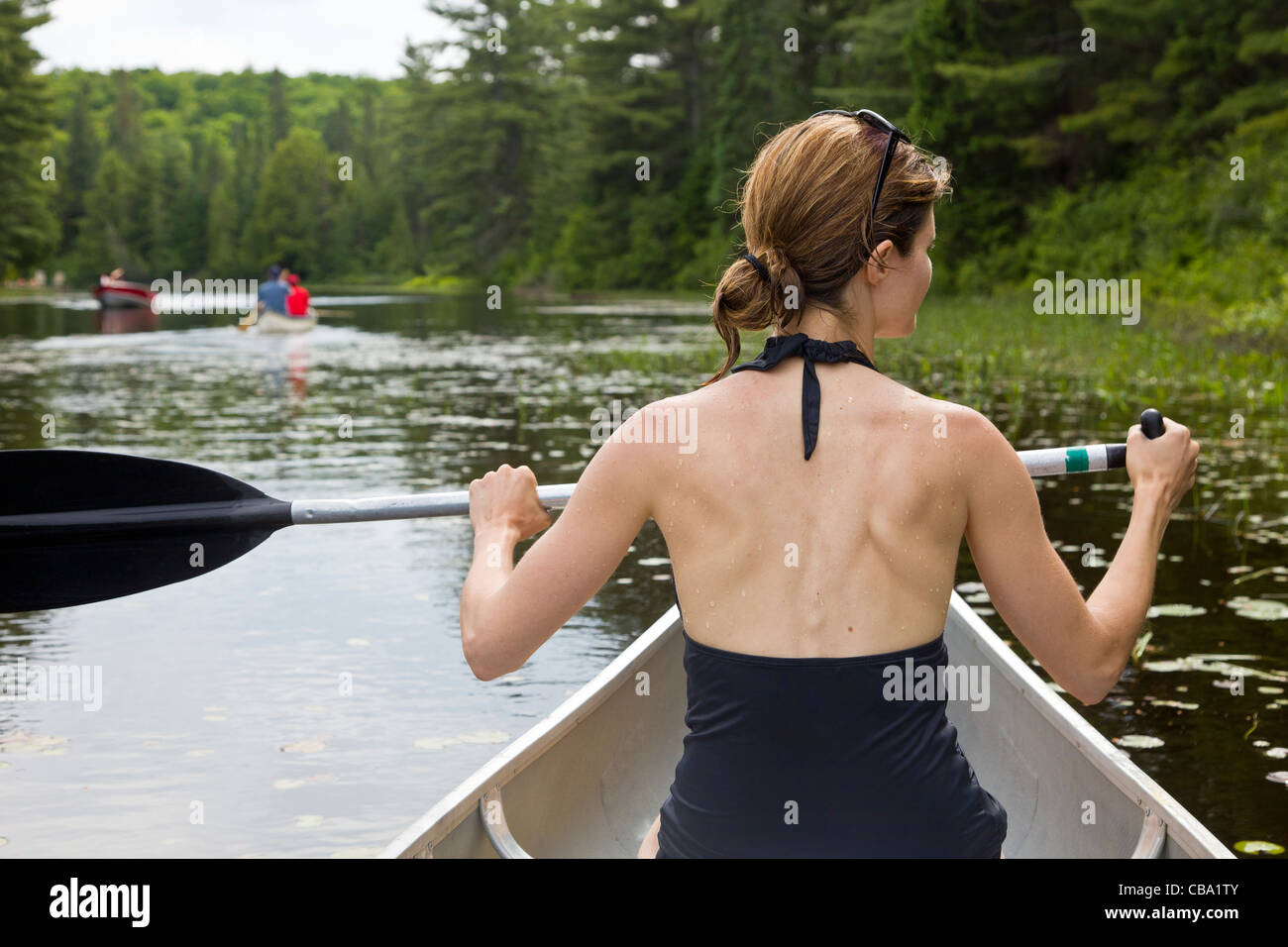 Woman paddling in a canoe along Rock Lake in Algonquin Park Stock Photo