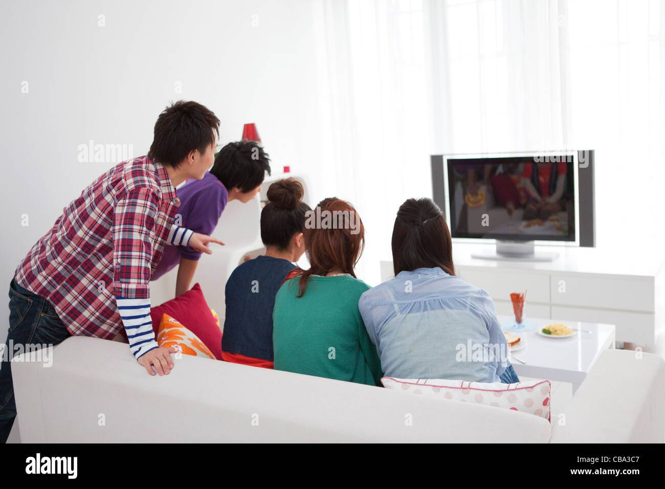 Young people watching TV Stock Photo - Alamy