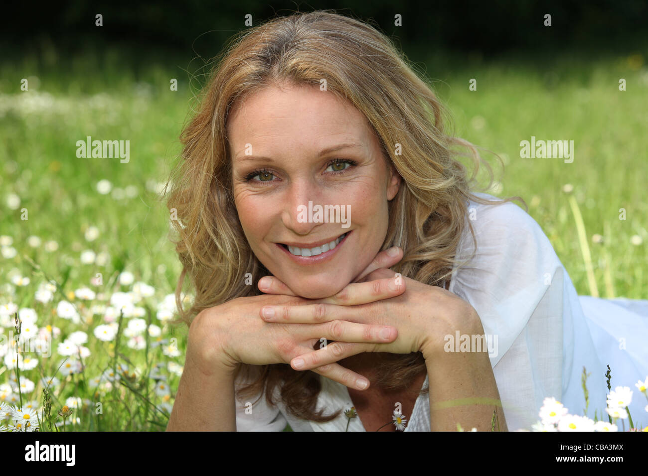 Smiling woman lying in a field of daisies Stock Photo - Alamy