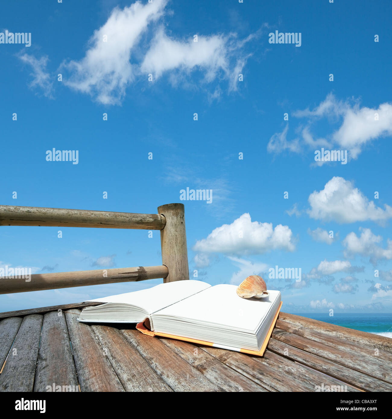 Book with a seashell on the bamboo chair at the beach. Square composition. Stock Photo