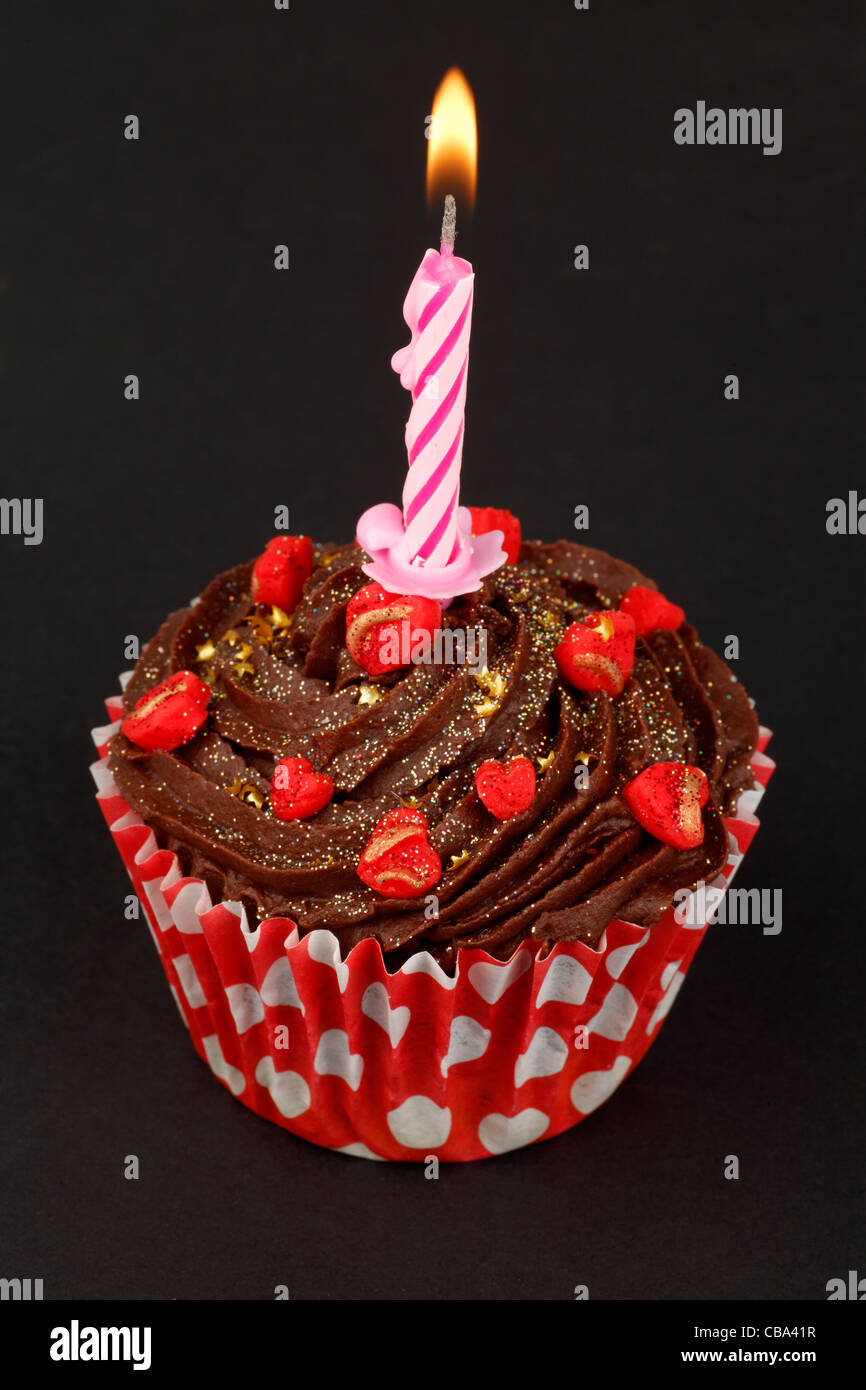 Cupcake with single lit candle on black background Stock Photo
