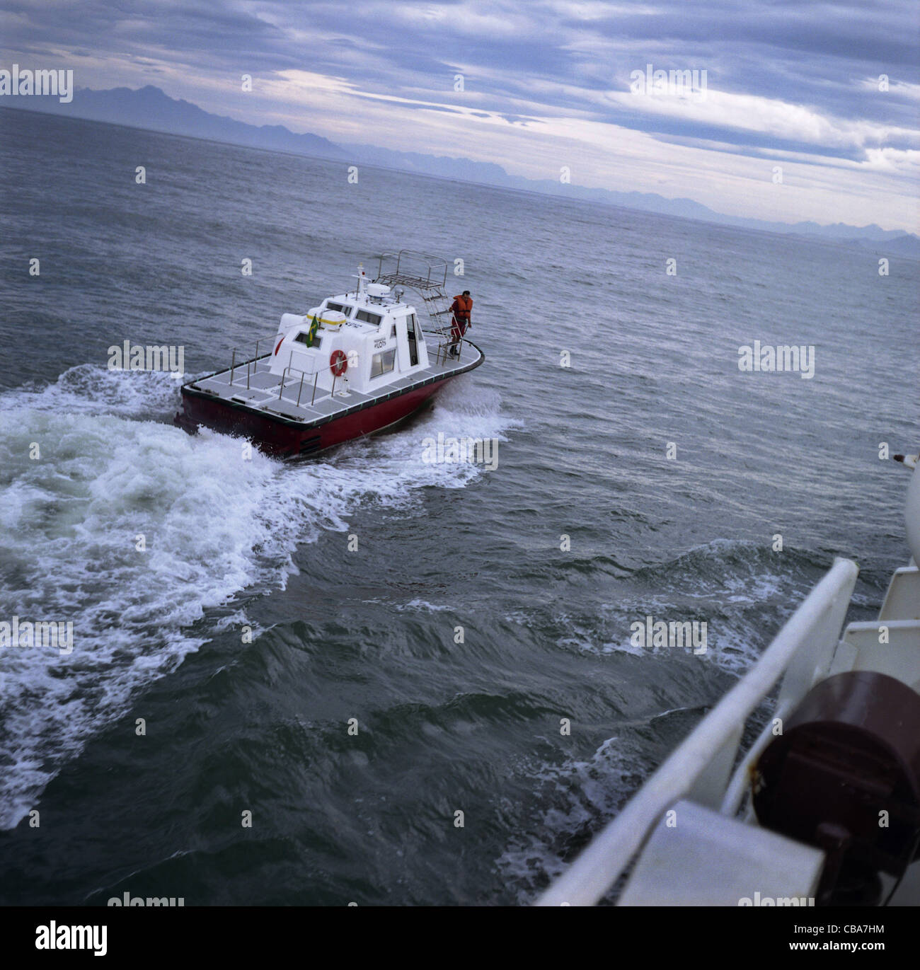Pilot launch boat beside ship, at sea. Stock Photo