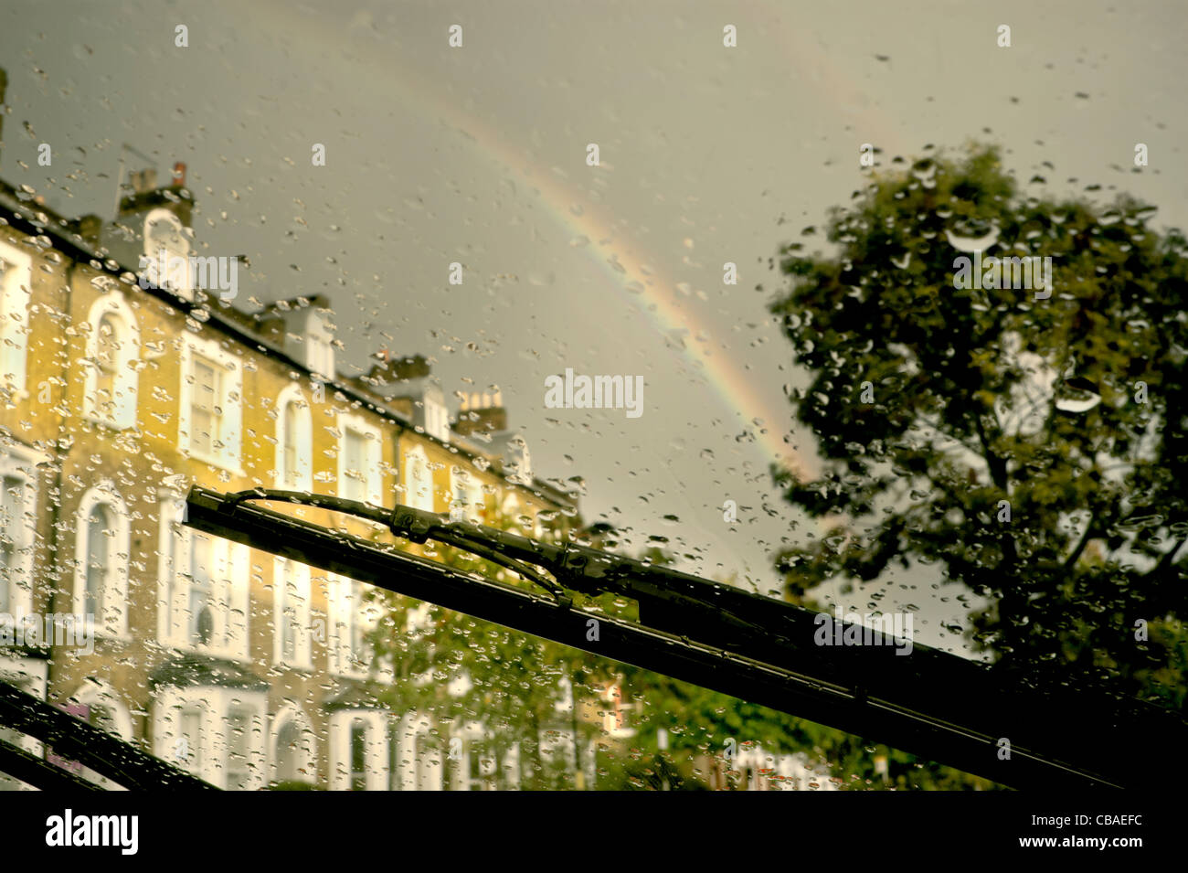 View from inside the car as the rain shower is usurped by the sun and a double rainbow appears. Stock Photo