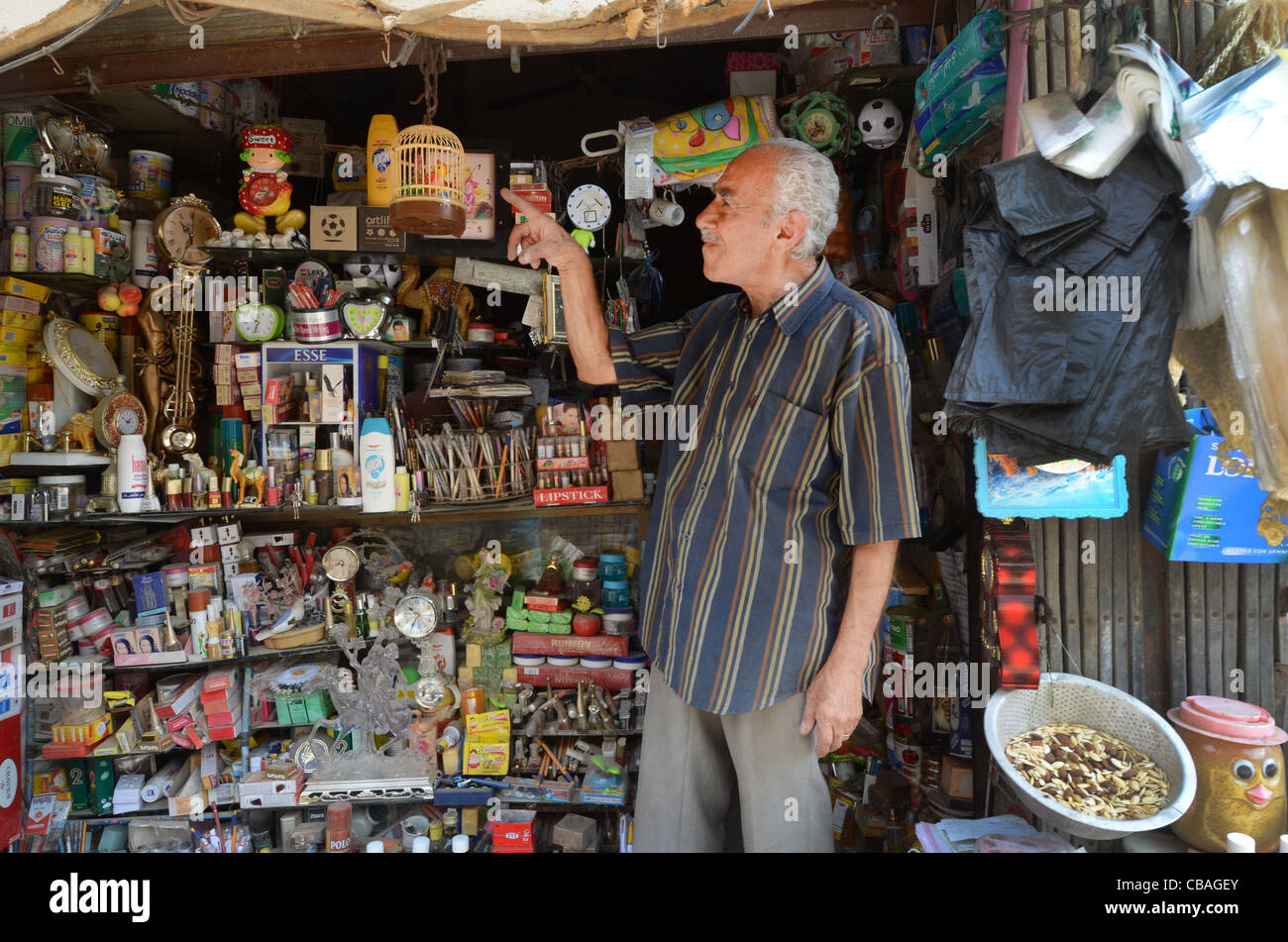 A shop keeper who seem to sell just about everything plays with a plastic cage bird at his shop in the old souk of Baghdad, Iraq Stock Photo