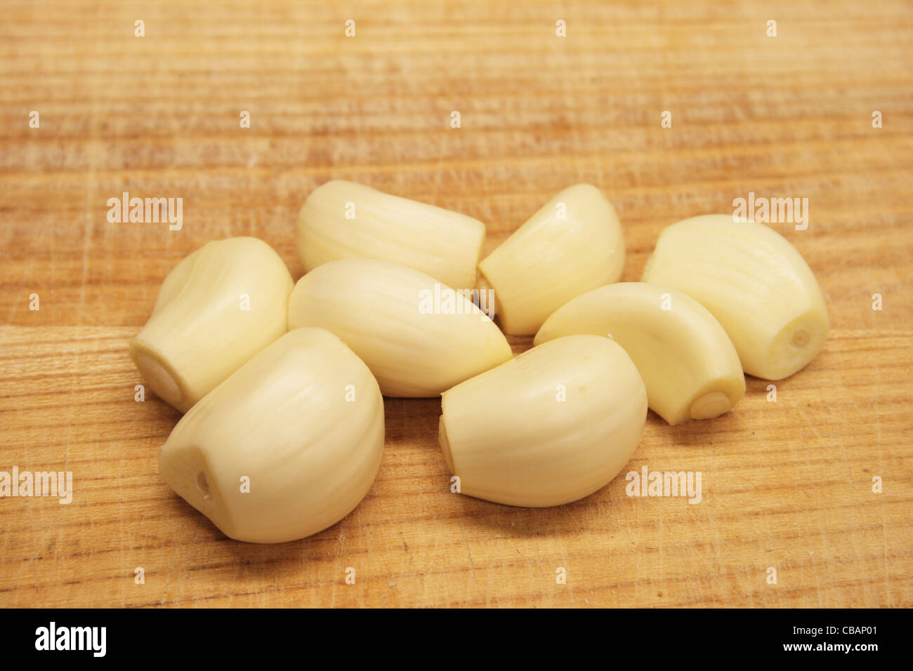 trimmed peeled garlic cloves on a wooden cutting board Stock Photo