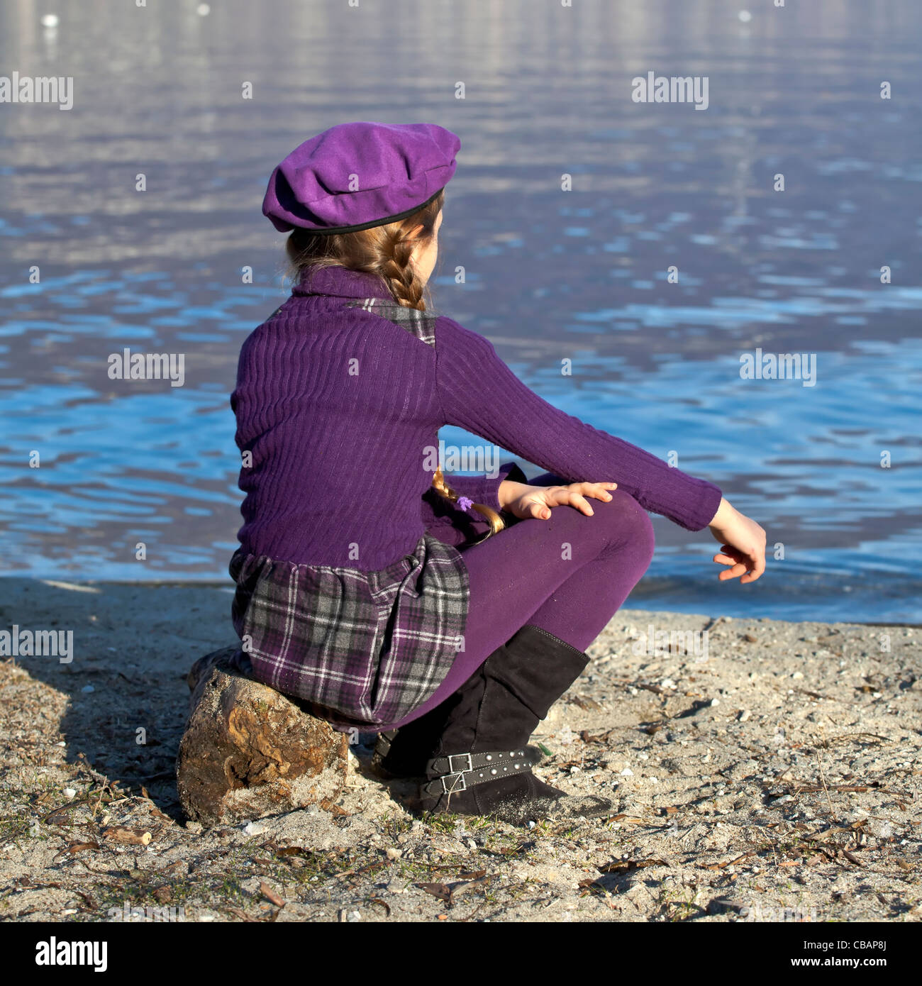 girl is sitting at the shore of a lake Stock Photo