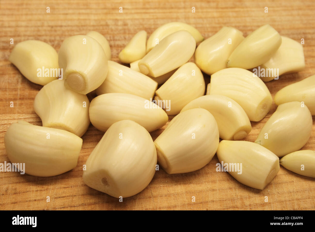 many trimmed peeled garlic cloves on a wooden cutting board Stock Photo