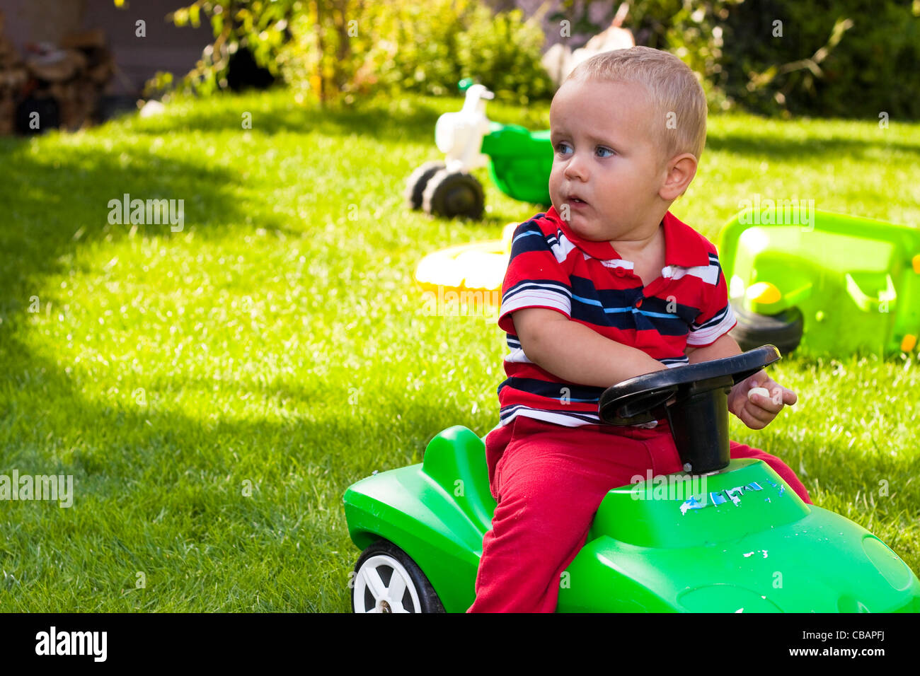 Toddler driving toy car in the garden Stock Photo Alamy