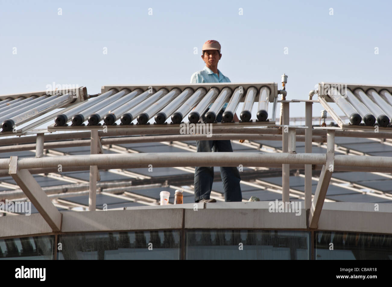 A worker on the roof of the Micro-E Hotel, world's largest solar powered hotel. China Solar Valley, Dezhou, Shandong, China Stock Photo