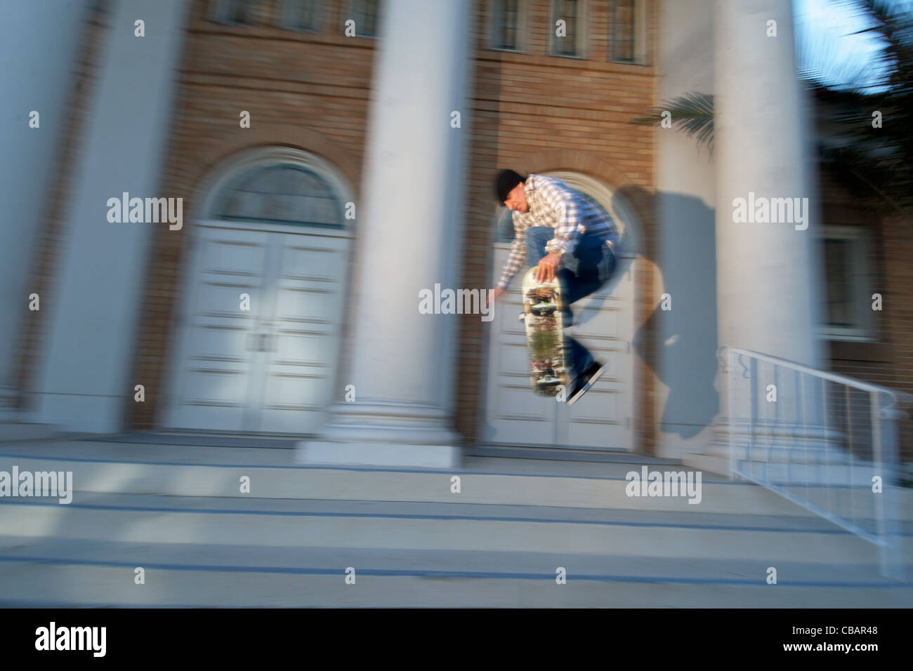 A male skateboarder jumping near stairs in an urban city setting. Stock Photo