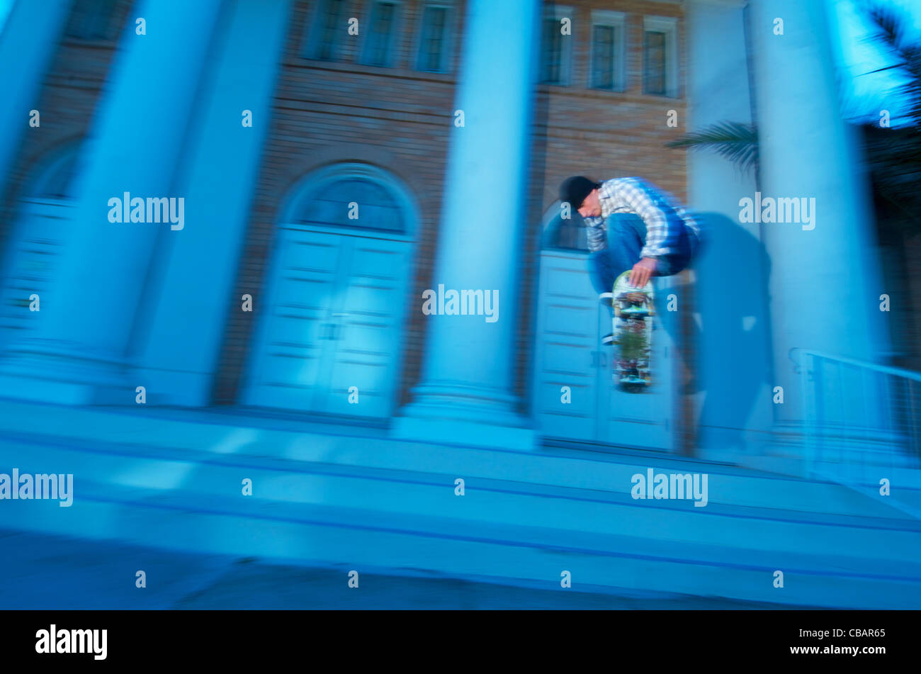 A male skateboarder jumping near stairs in an urban city setting. Stock Photo