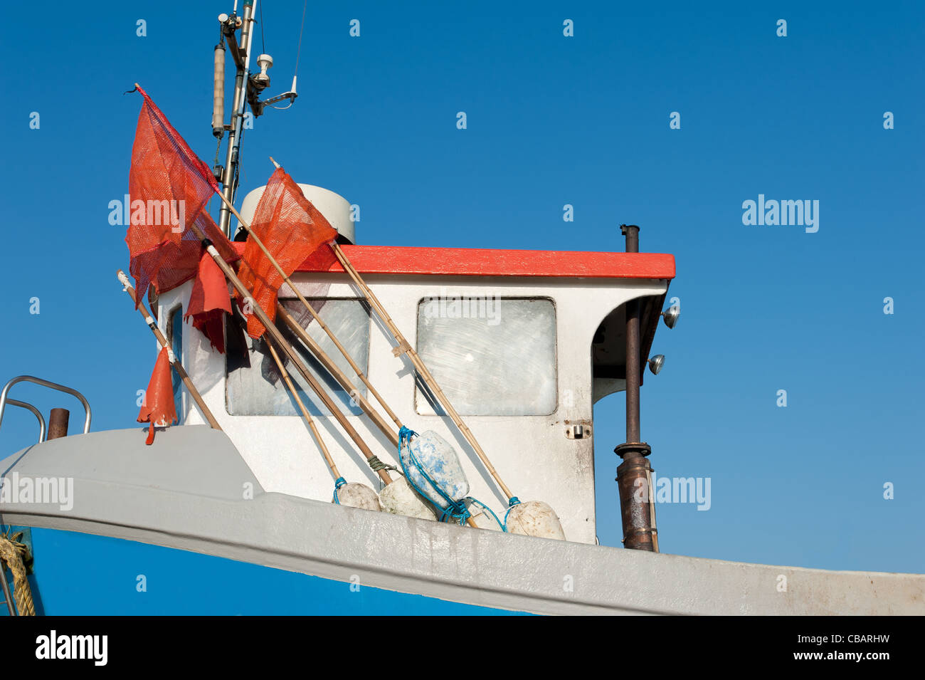 Close-up on a small fishing trawler with its colourfully flagged buoys and perfect blue sky. Image taken at Hythe, Kent, UK Stock Photo