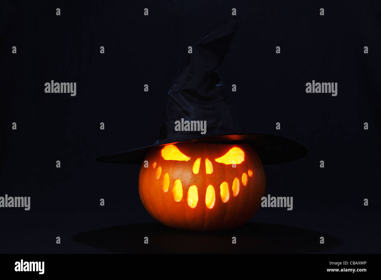 Halloween pumpkin lantern with evil face and witches hat lit with a candle Stock Photo