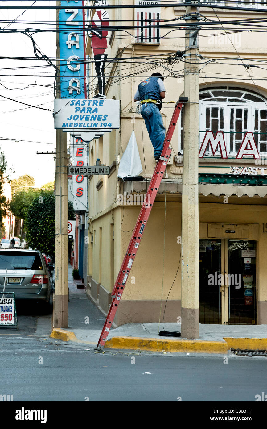 telephone lineman on ladder leaning against streetcorner pole working
