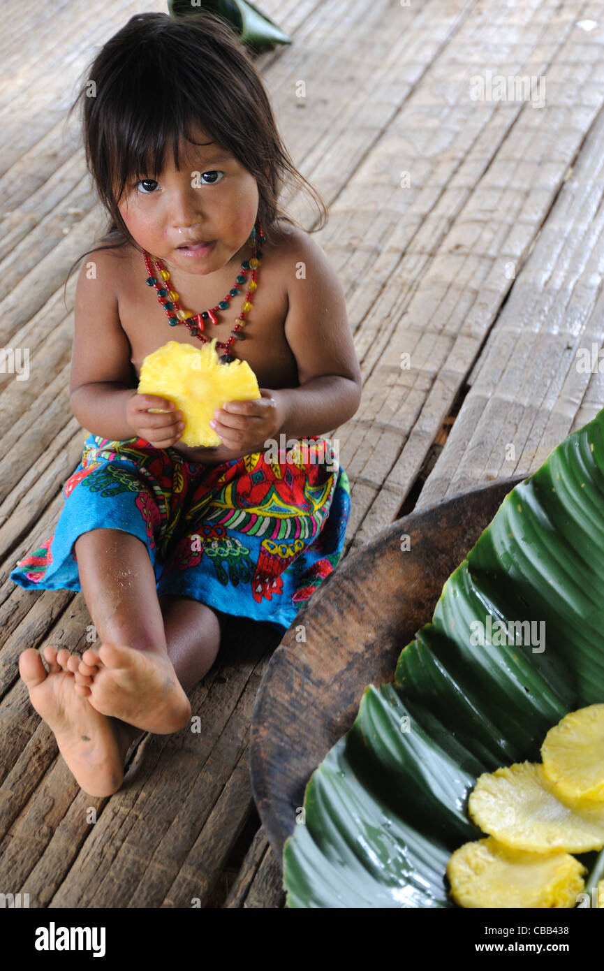 Embera indian little girl eating pineapple at Embera Puru indigenous community, Panama Stock Photo