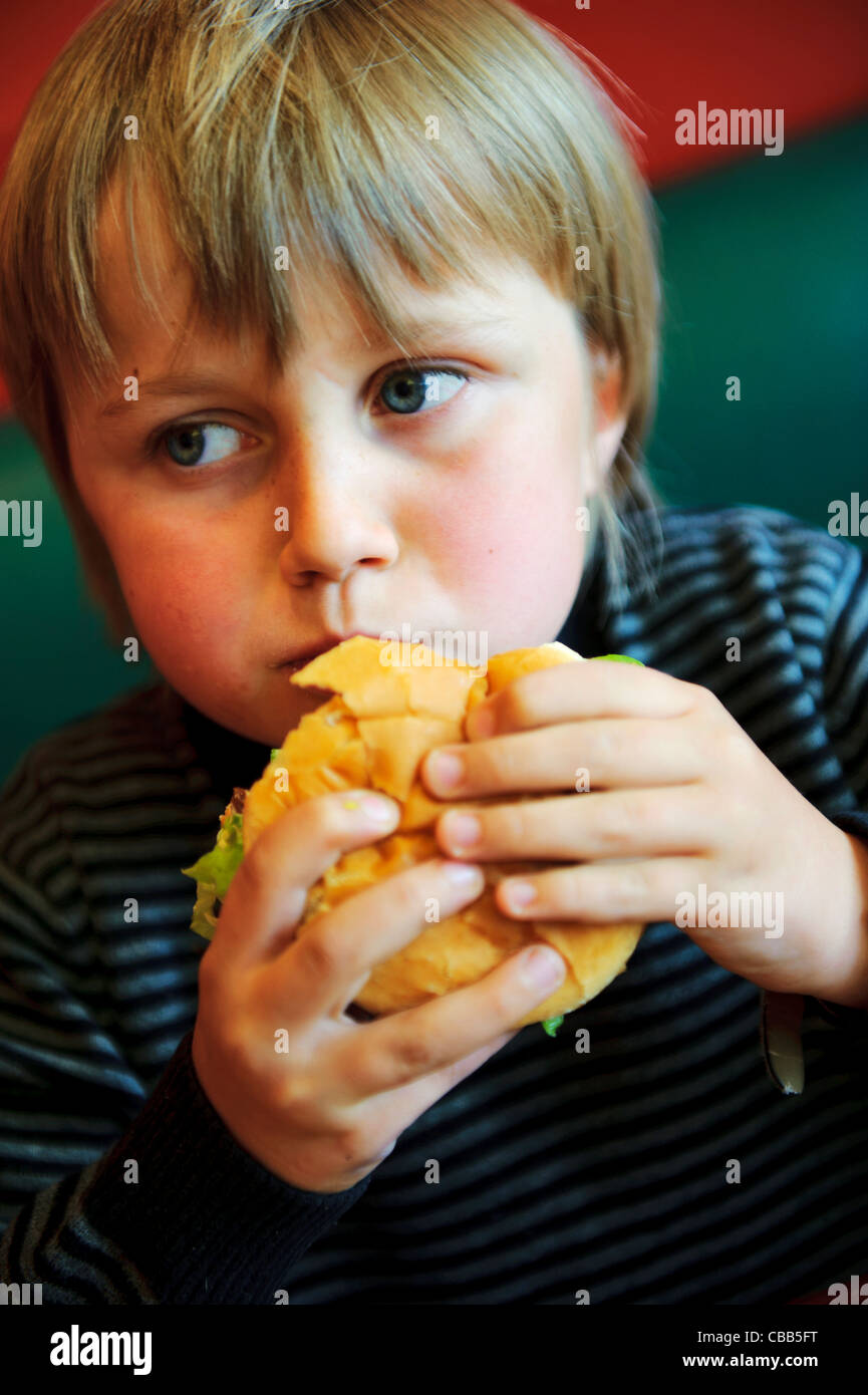Stock photo of an 11 year old boy eating a burger. Stock Photo