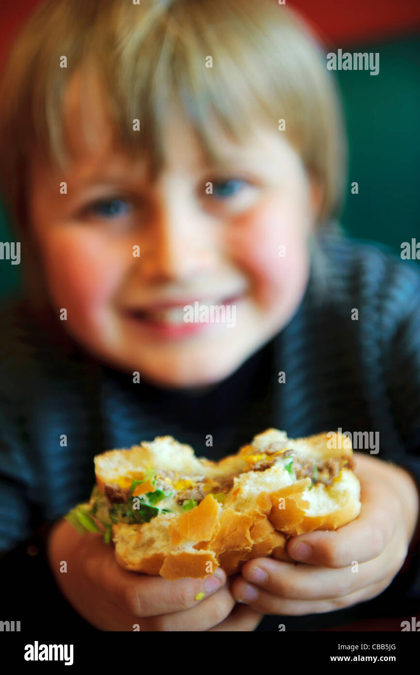 Stock photo of an 11 year old boy eating a burger. Stock Photo