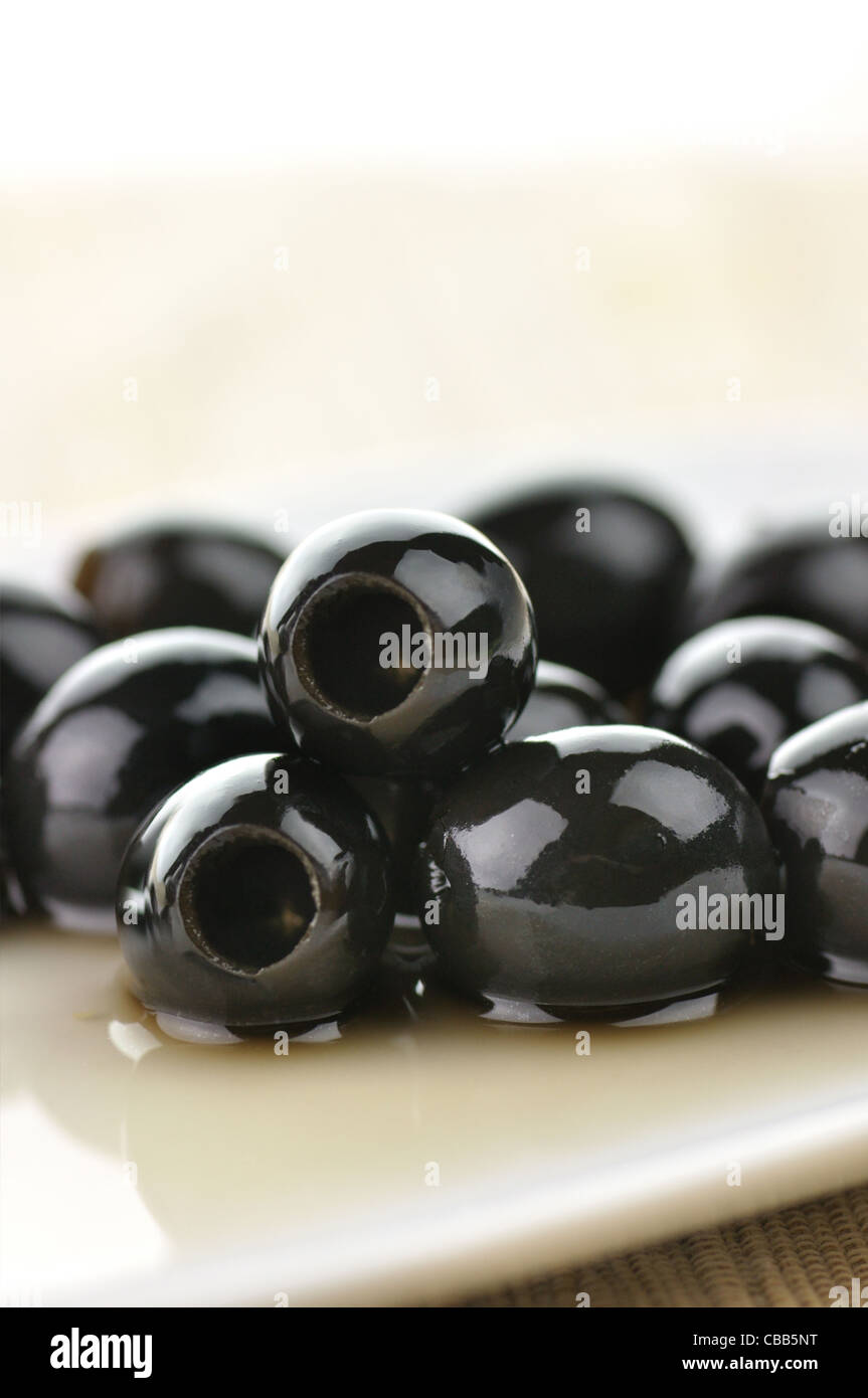 big black olives in a white plate, close up Stock Photo