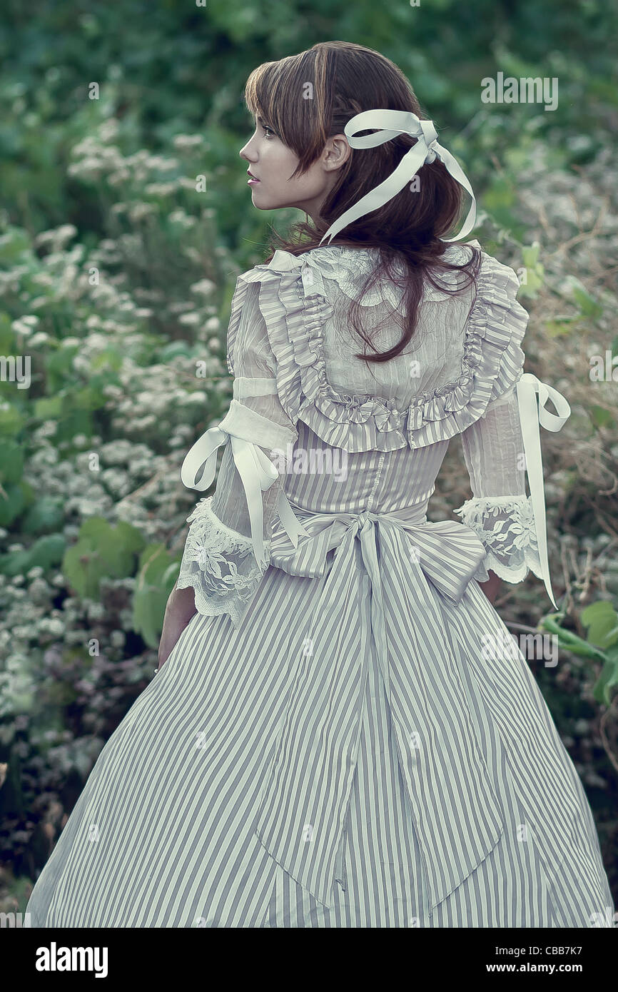 A girl wearing a vintage dress in a garden with back to camera Stock ...