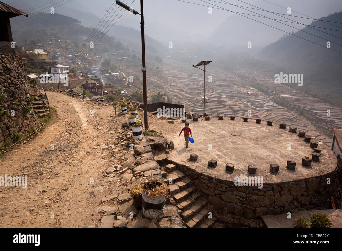 India, Nagaland, Khonoma, eco-village, child on circular Khel meeting place above terraced farmland Stock Photo