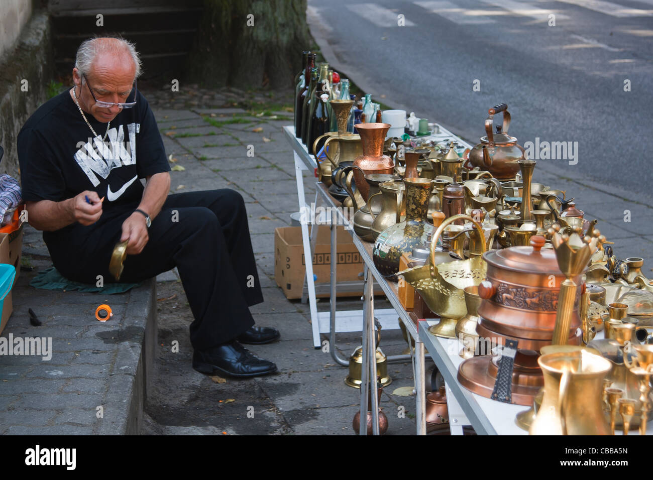 A Man Selling Various Vintage Brass Articles On Flea Market Stall