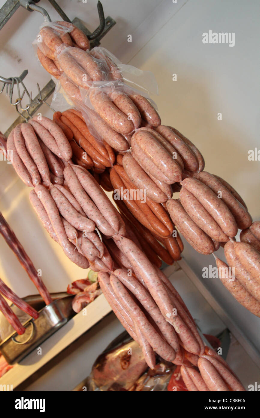 a variety of sausage links hanging up in a butcher's refrigerator Stock