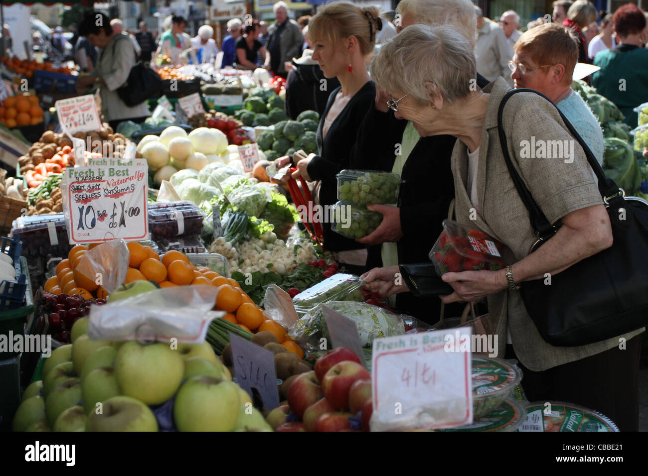 shoppers selecting fresh fruit and vegetables from a busy market stall