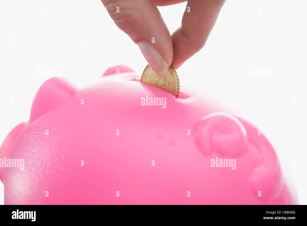Close up of woman feeding piggy bank Stock Photo