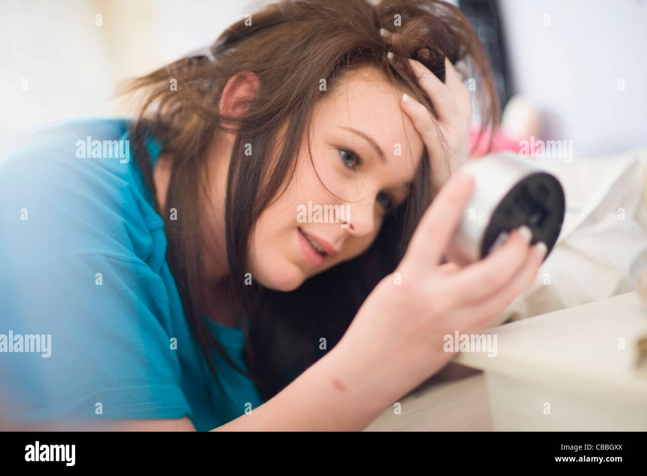 Teenage girl checking alarm clock Stock Photo Alamy