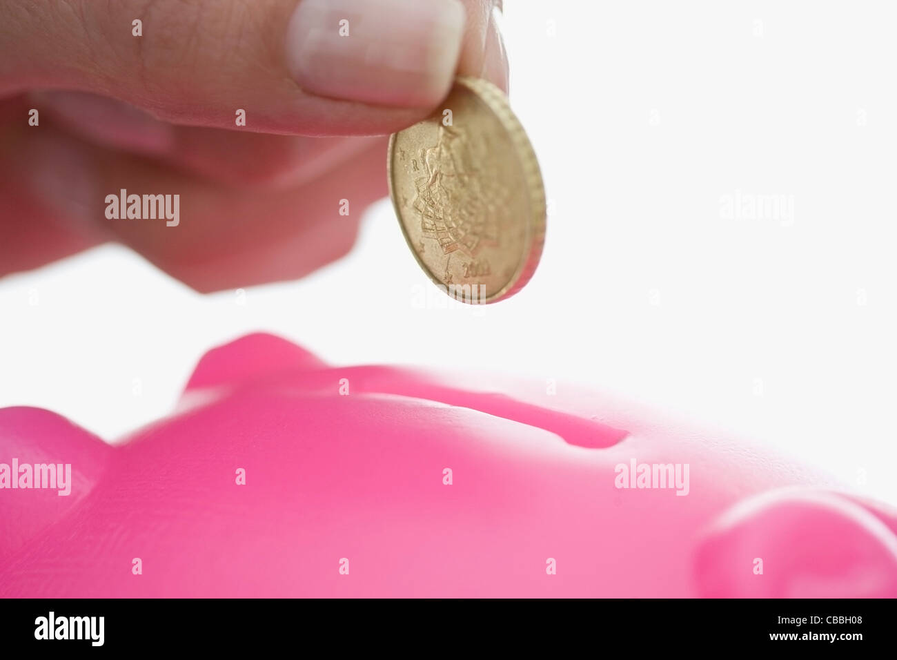 Close up of woman feeding piggy bank Stock Photo