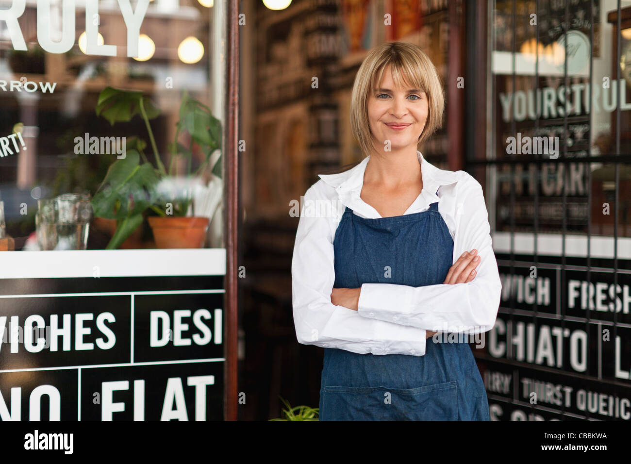 Smiling waitress standing in cafe Stock Photo