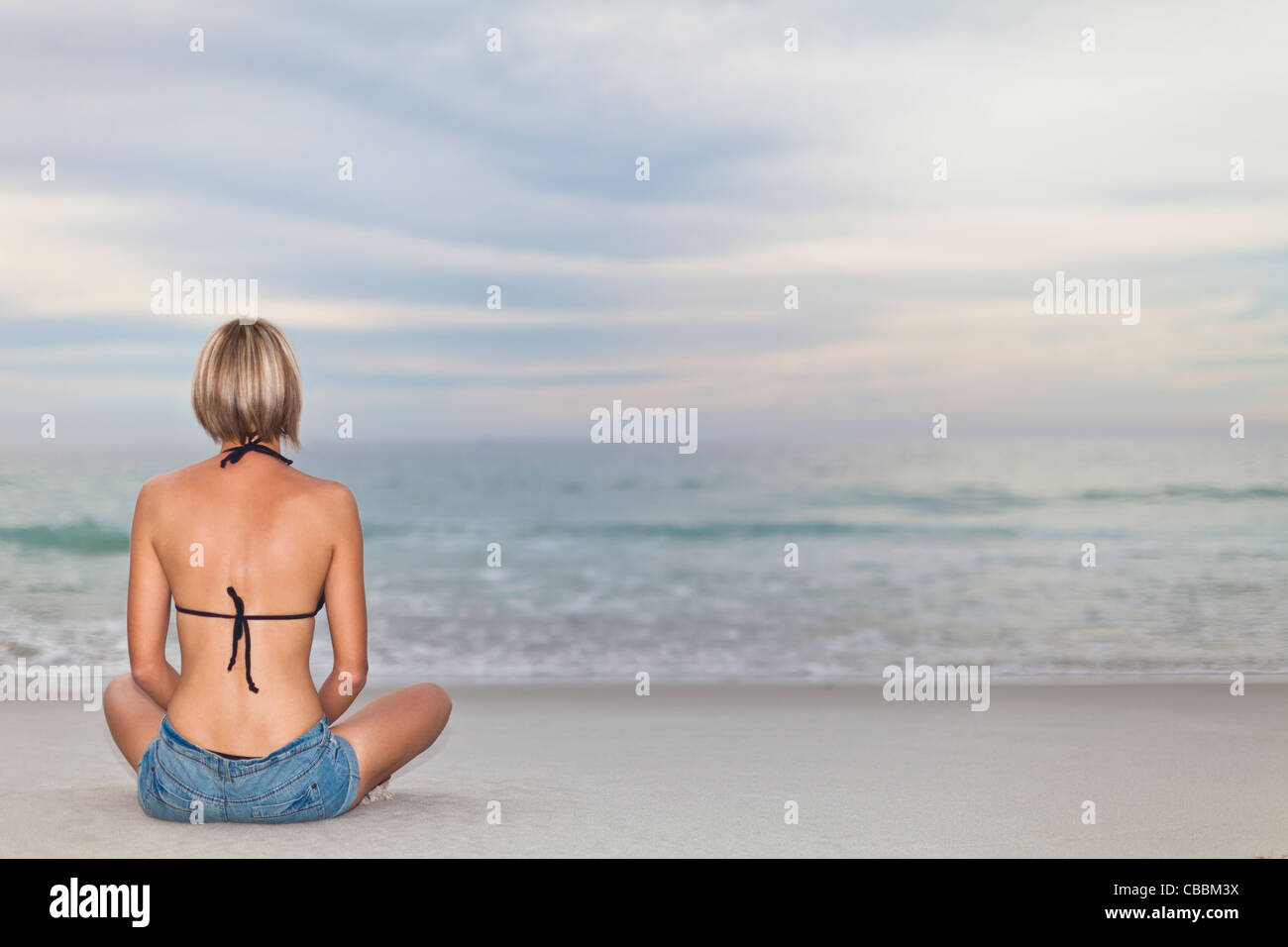 Woman sitting cross legged on beach Stock Photo
