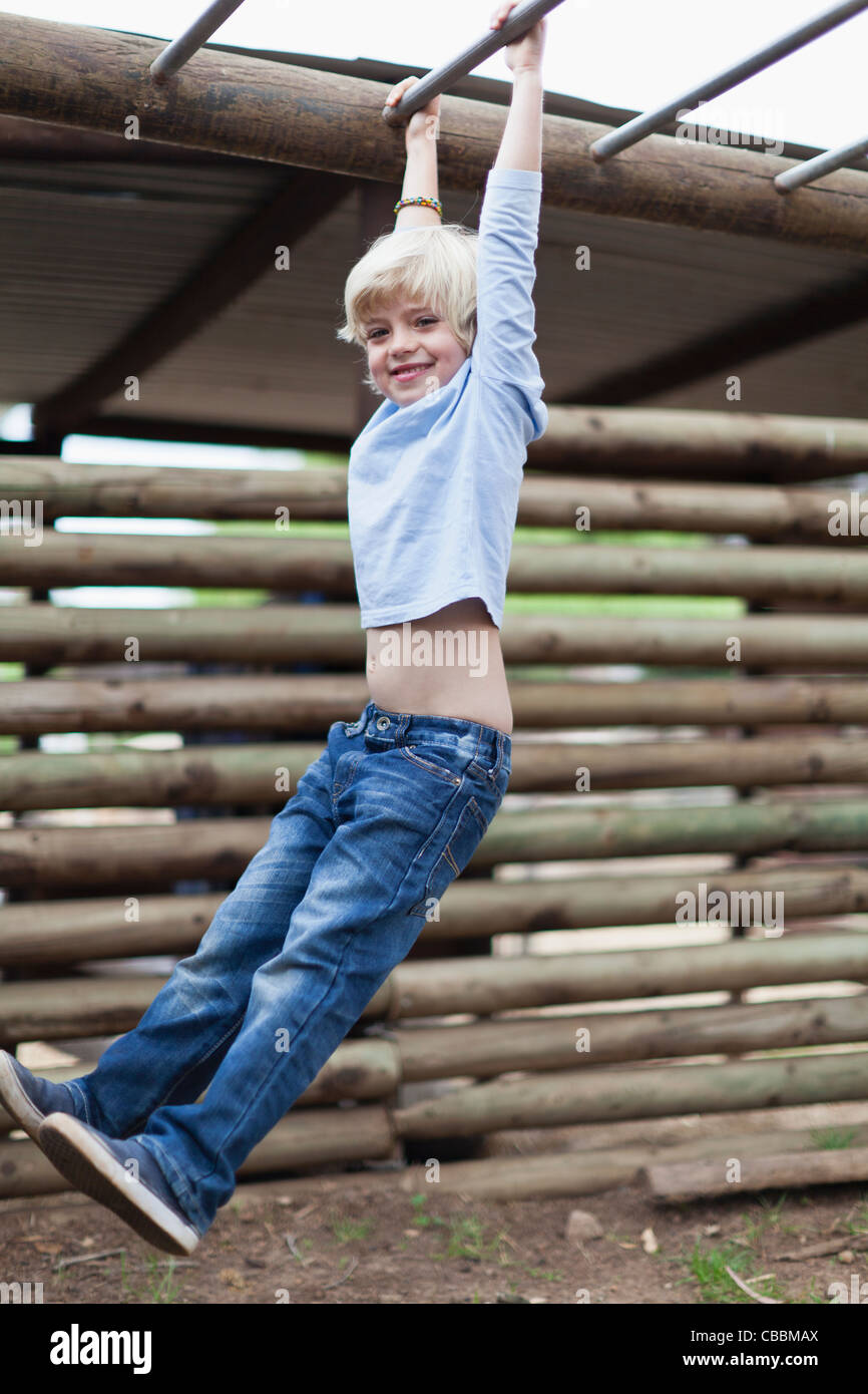 Boy swinging from monkey bars Stock Photo