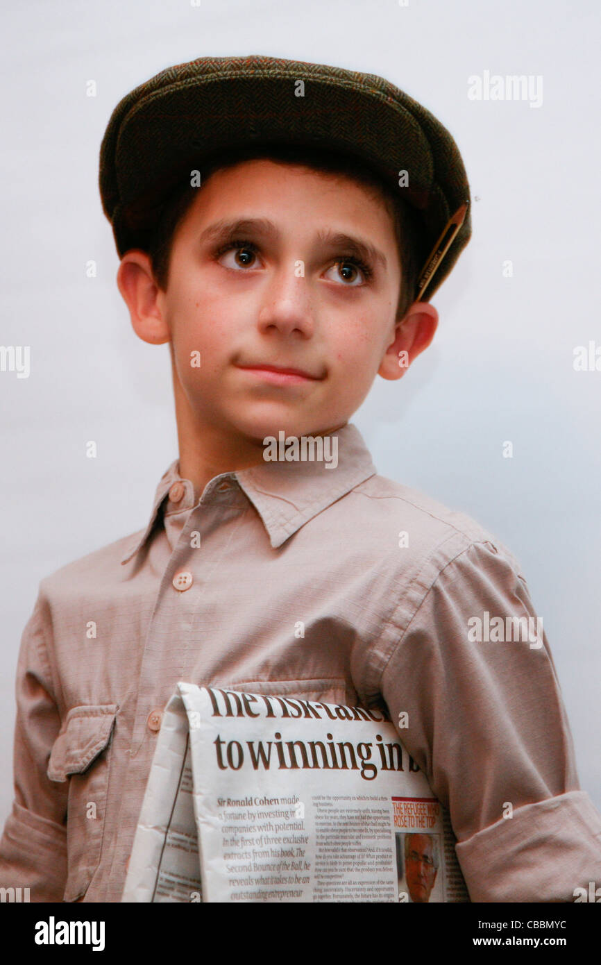 Boy in flat cap holding newspaper, pencil behind ear! Stock Photo