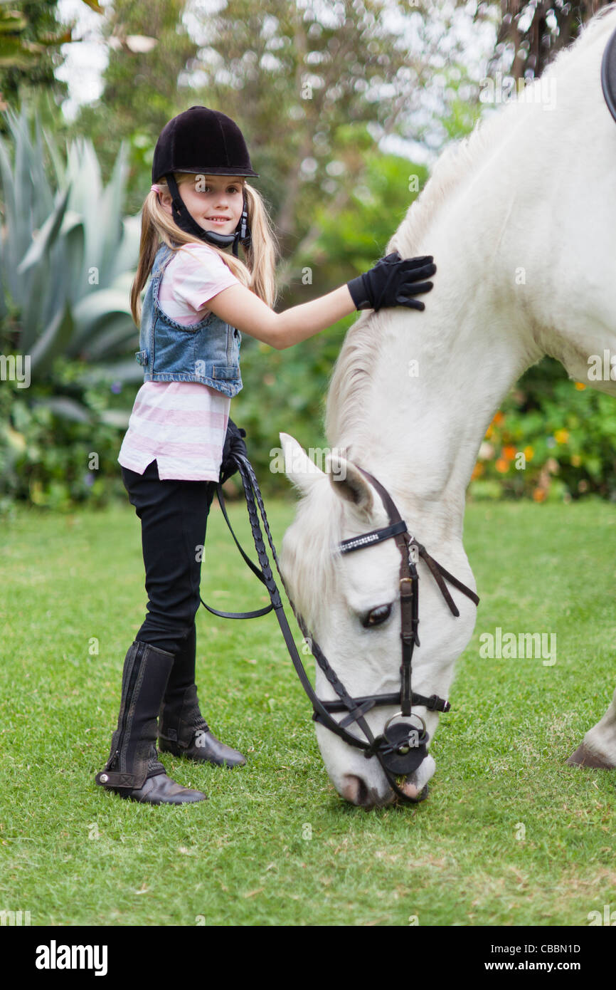 Girl petting grazing horse in park Stock Photo