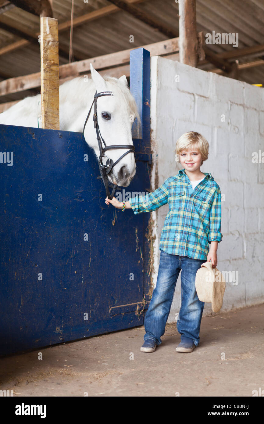 Boy standing with horse in stable Stock Photo Alamy