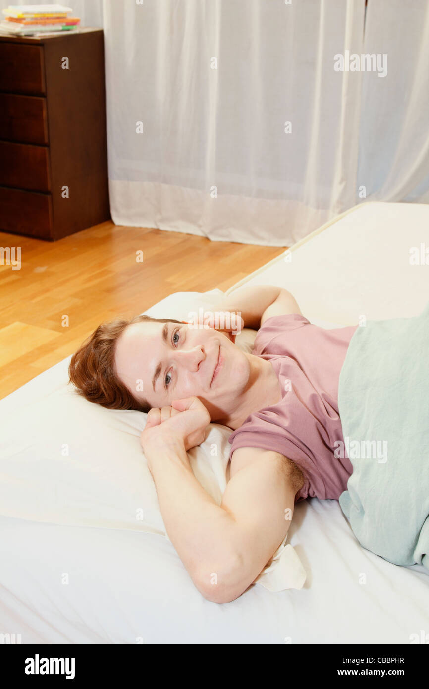 Smiling man stretching in bed Stock Photo