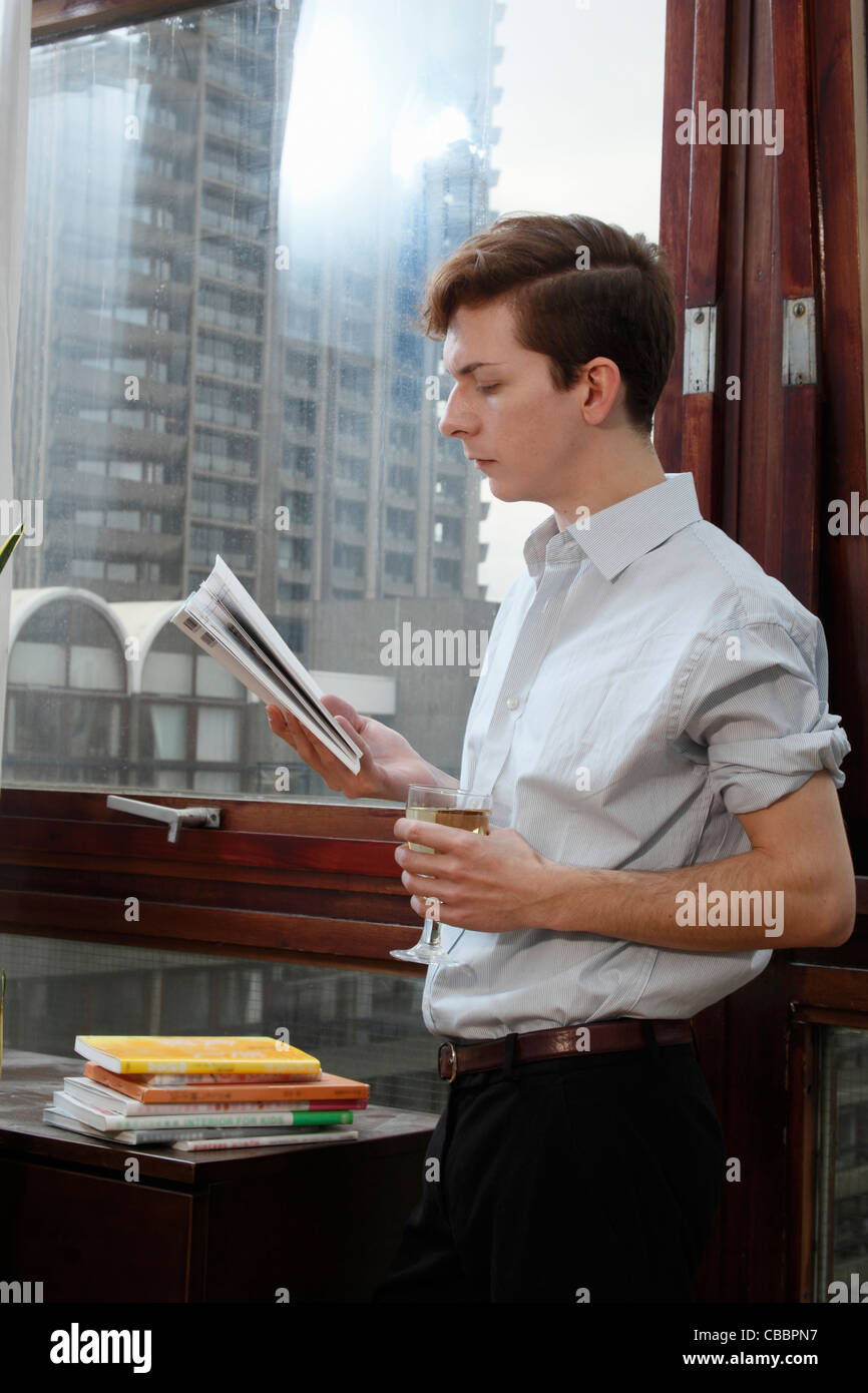 Businessman reading magazine with wine Stock Photo