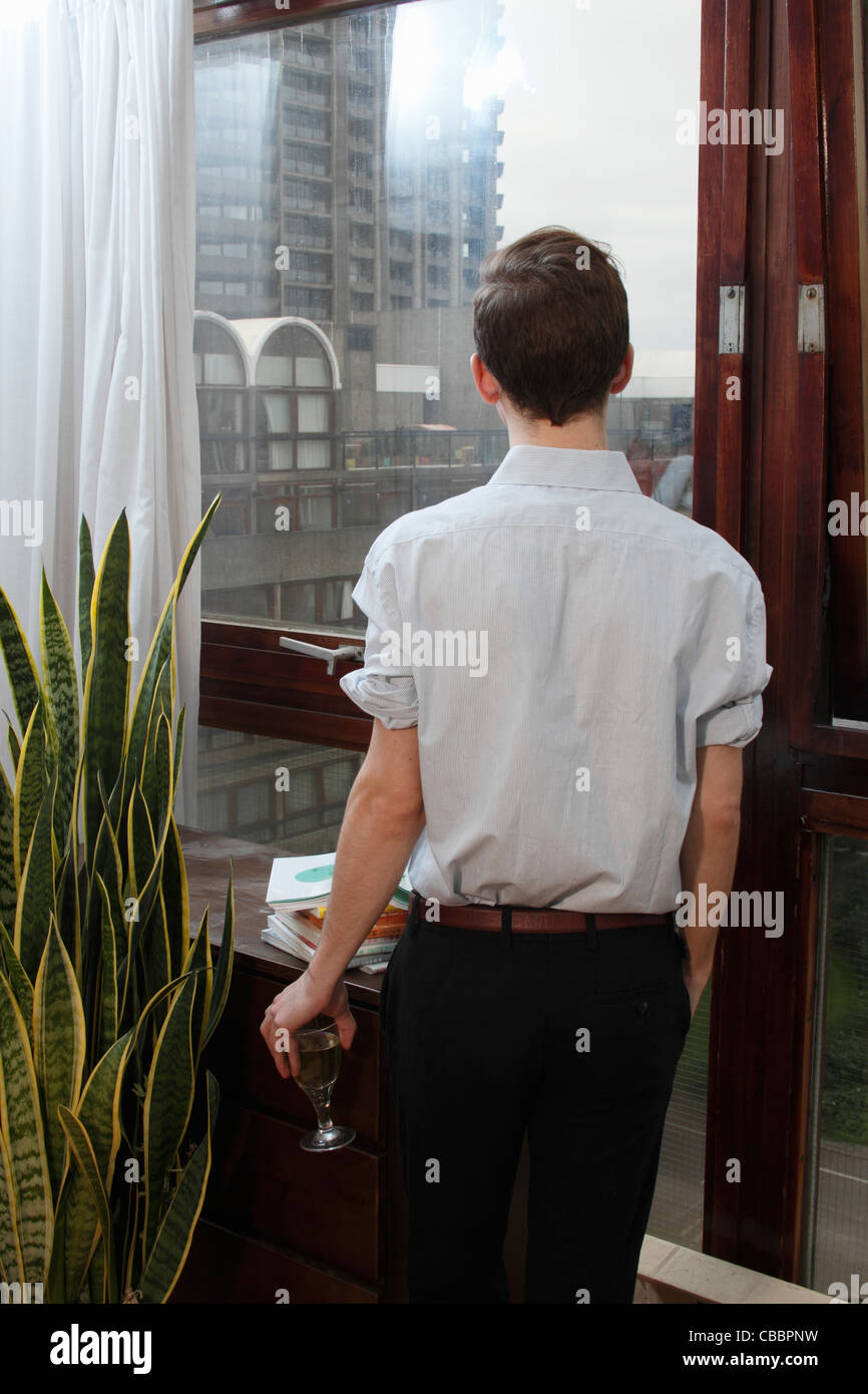 Businessman with wine looking out window Stock Photo