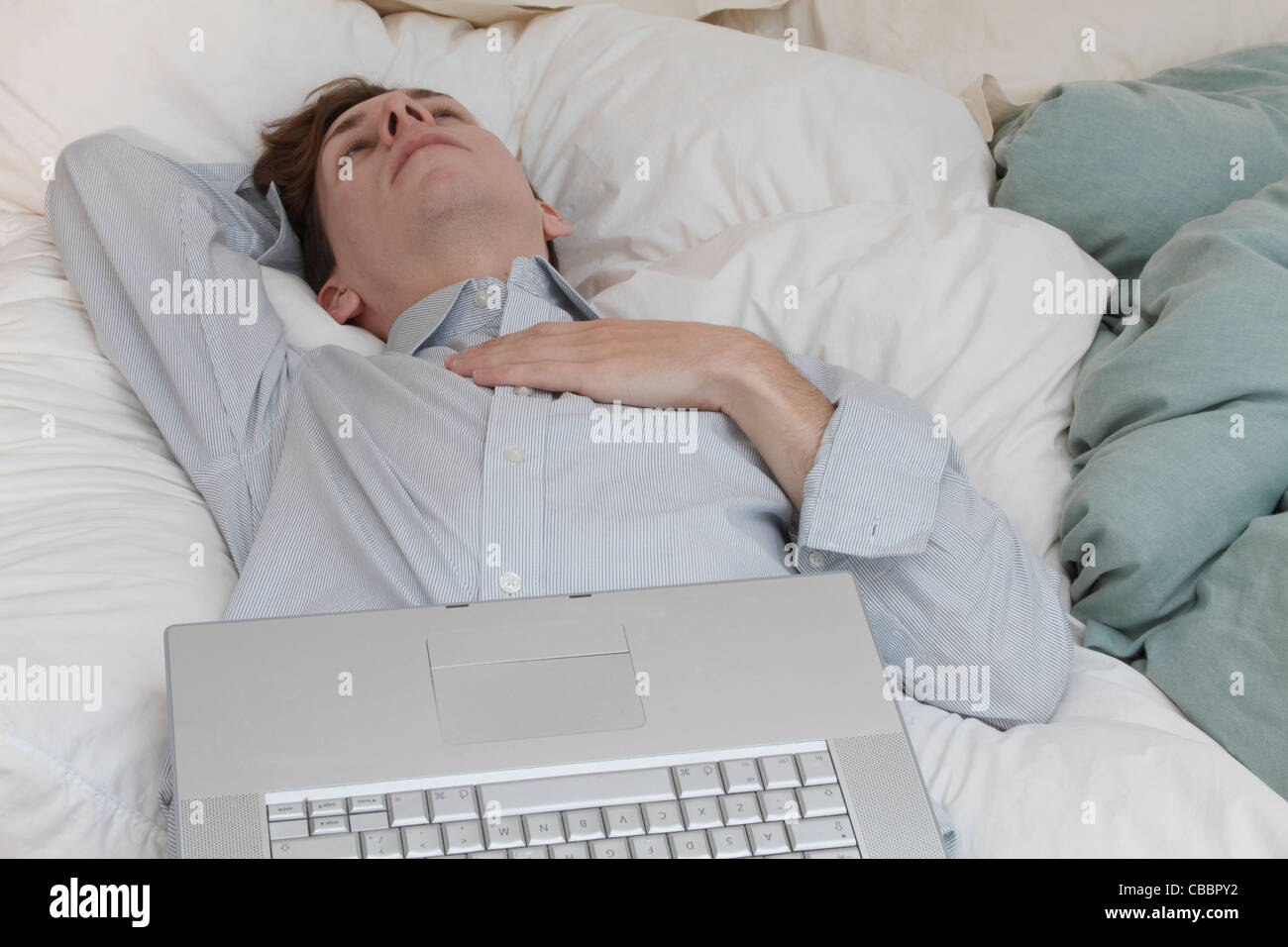 Businessman with laptop laying on bed Stock Photo Alamy