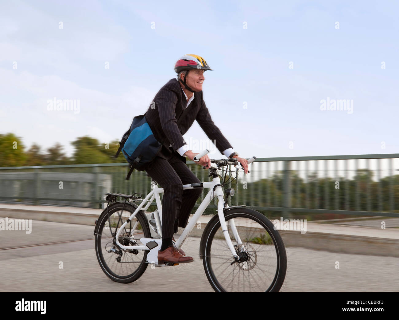 Businessman riding bicycle on bridge Stock Photo