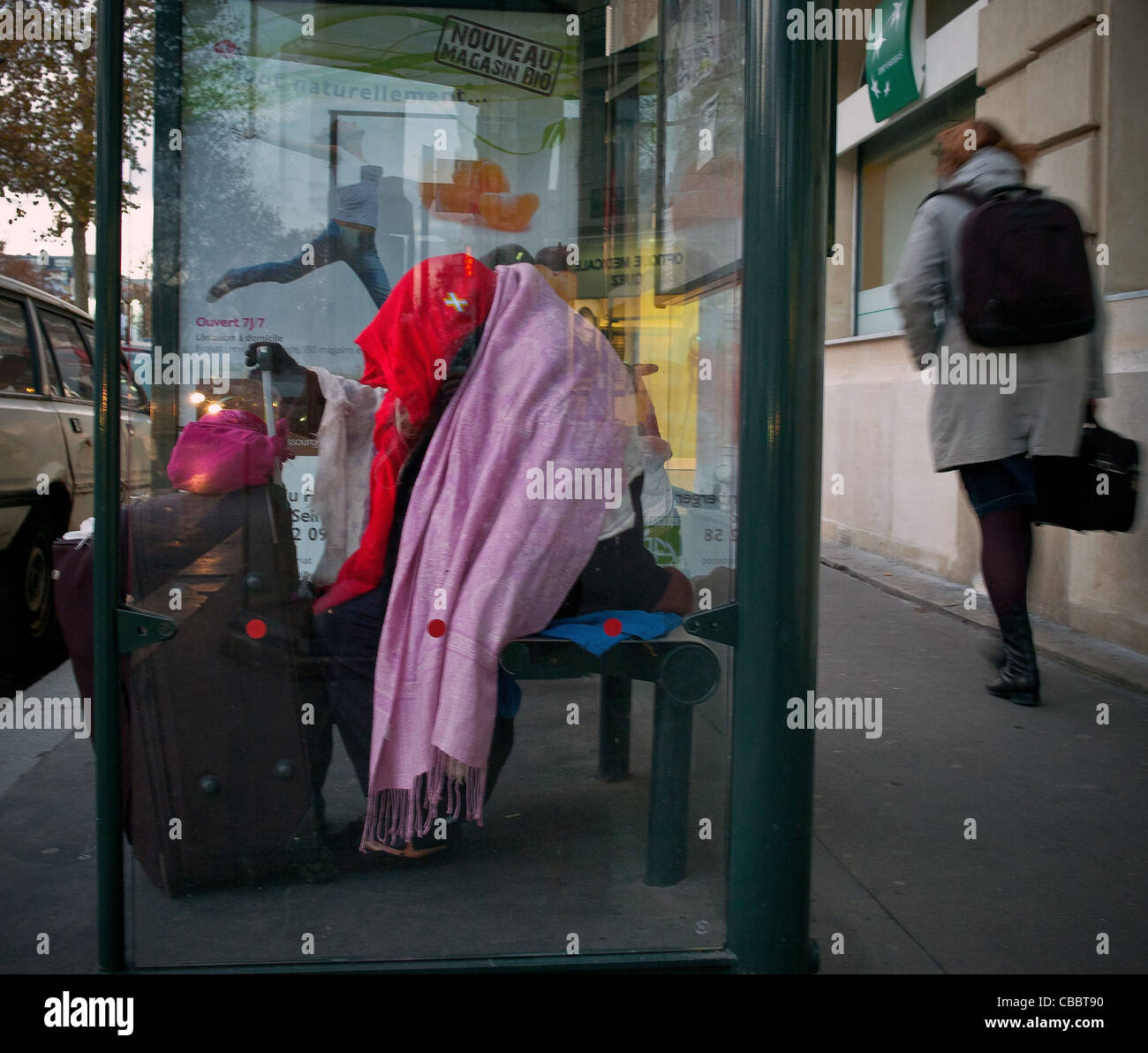 urban misery, Modern times. Bus shelter in Neuilly sur Seine, a sleeping homeless the day it's cold night and often fear Stock Photo