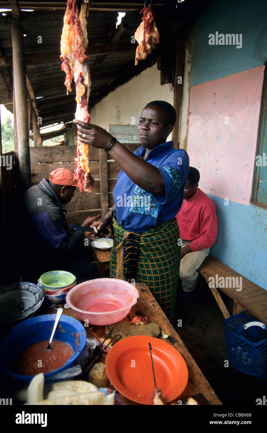Woman cutting meat in a local restaurant, Mwika, Kilimanjaro Region, Tanzania Stock Photo