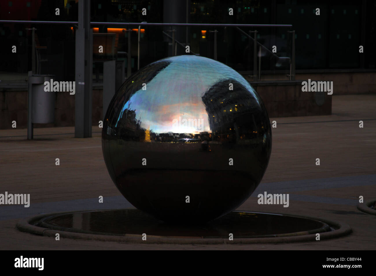 Stainless Steel Sphere and Bright Sky Reflection with Orange Clouds And A Building On Early Evening Stock Photo