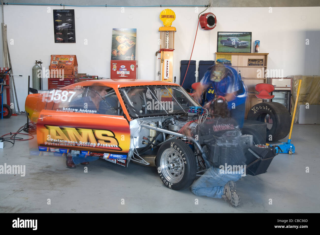 Enthusiasts working on a drag racing Ford Mustang in their workshop garage. Stock Photo