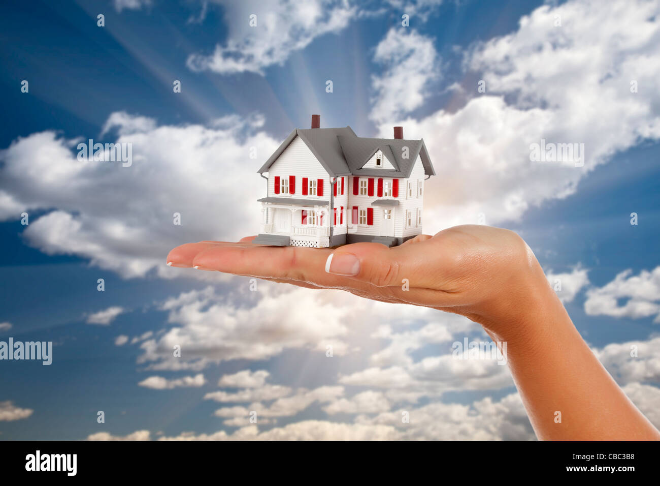 Model House in Female Hand on a Cloud and Sky Background Stock Photo ...