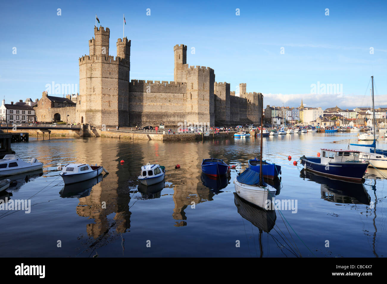 A bright summer evening at Caernarfon Castle, Gwynedd, North Wales. The castle is reflected in the River Seiont. Stock Photo