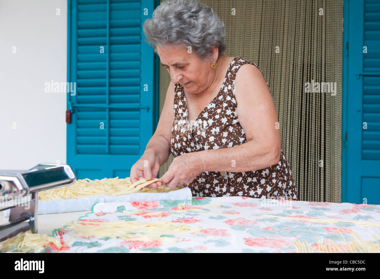 Older woman making pasta with roller Stock Photo